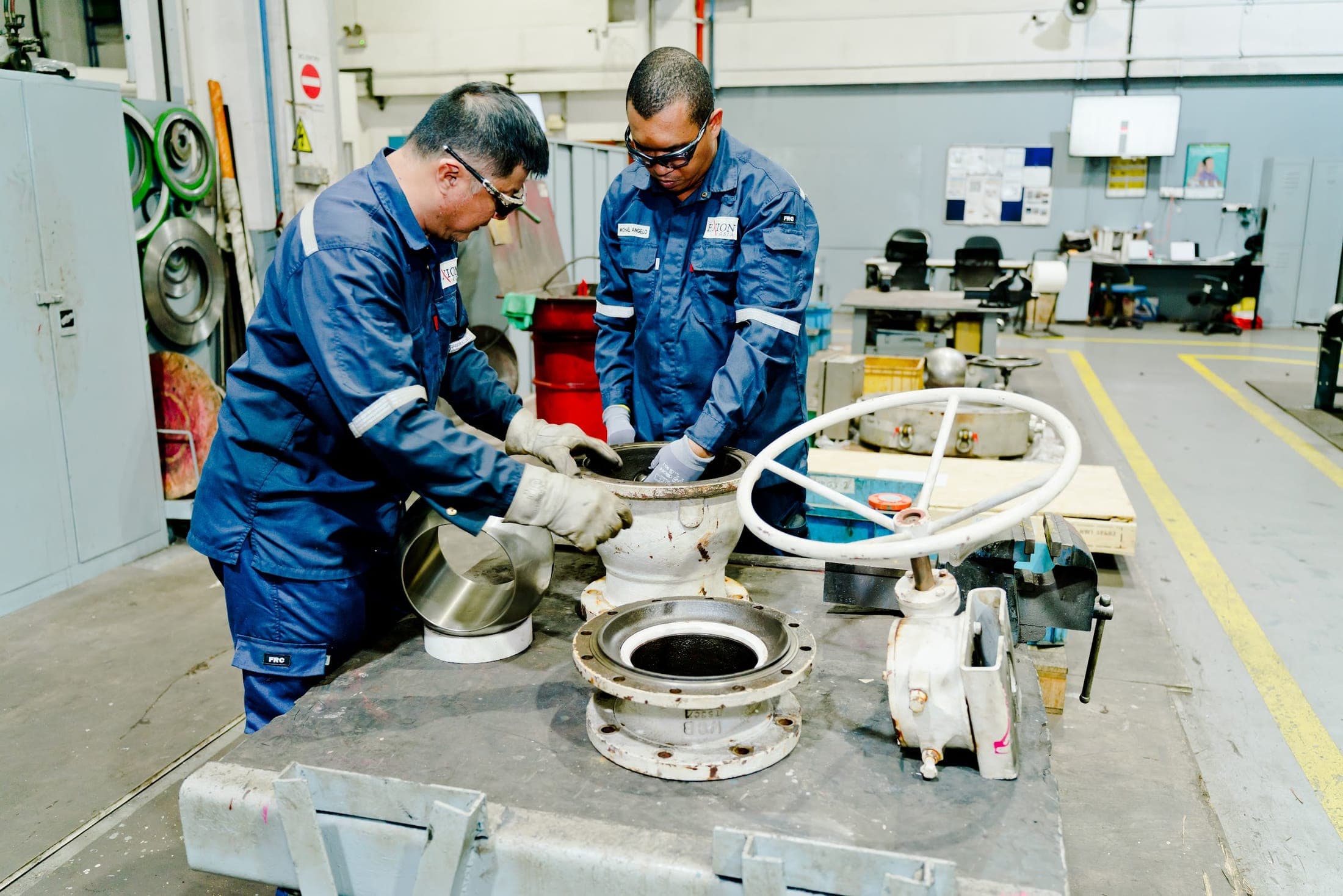 Two Exion technicians overhauling valves on the workshop bench