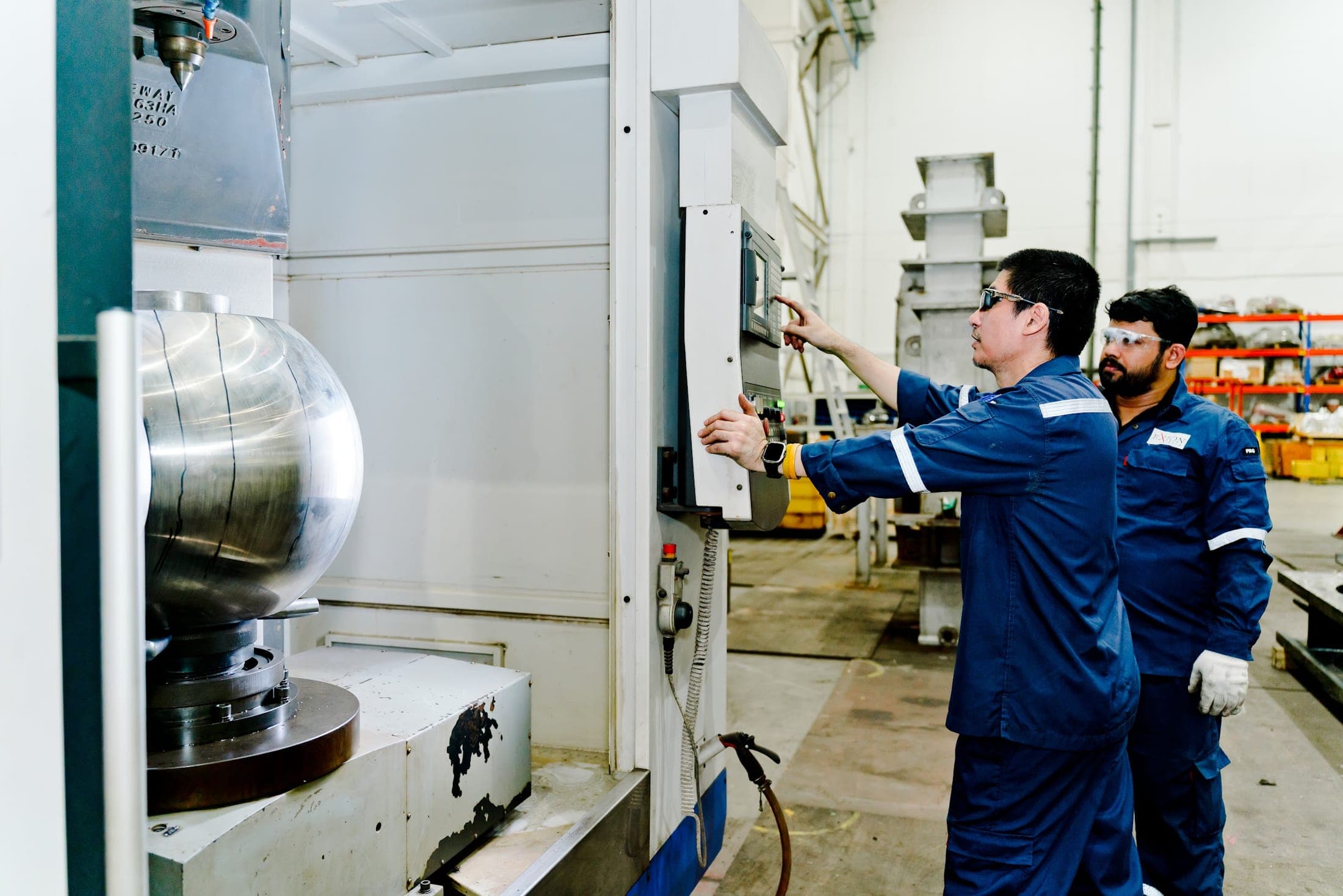 Engineers machining a large steel component on the CNC machine